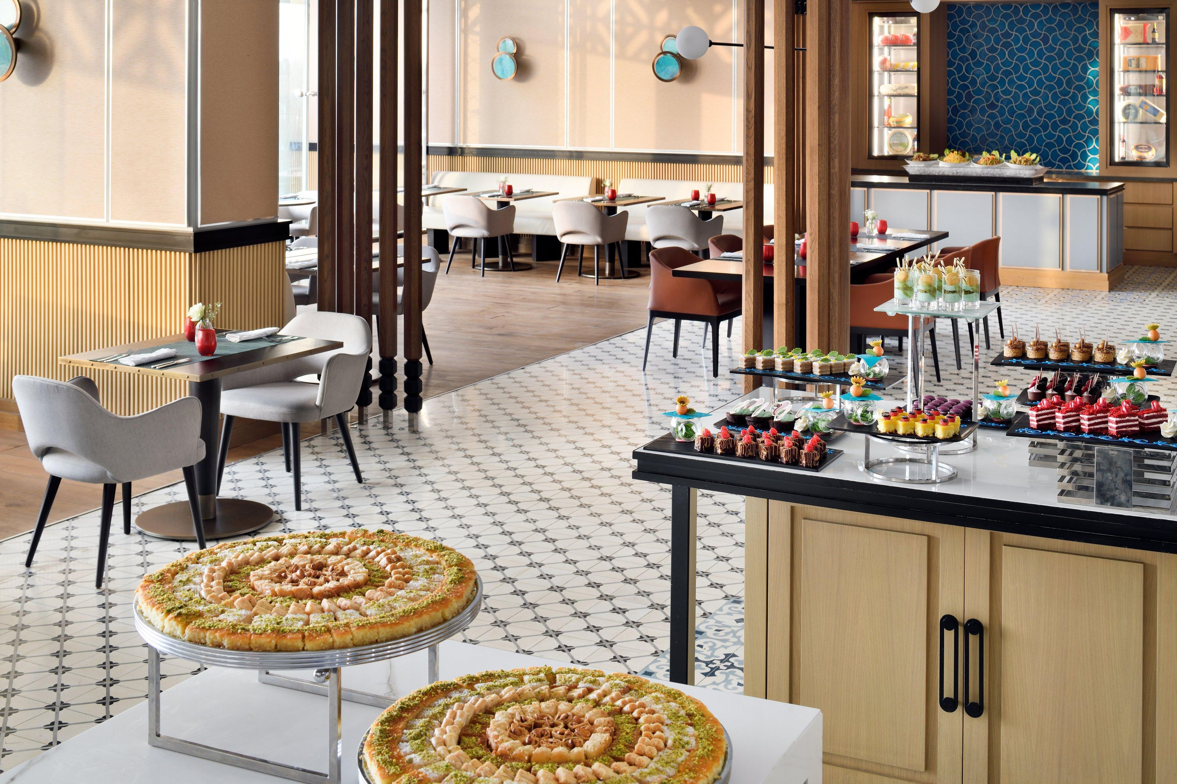 A restaurant with a central bar area, multiple seating options, and a variety of desserts displayed on the counter.