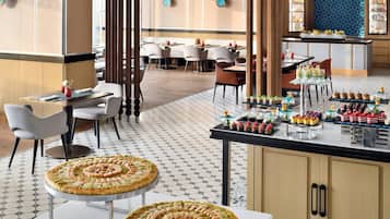 A restaurant with a central bar area, multiple seating options, and a variety of desserts displayed on the counter.