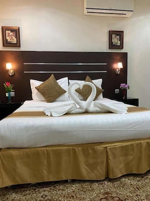 A hotel room with a large bed, two wall-mounted lamps, and two framed pictures on the walls. - Rest Night Serviced Apartments - AL Nafal (Riyadh)