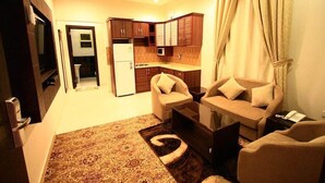 A compact living space with a kitchenette, a sofa set, and a patterned rug. - Rest Night Serviced Apartments - AL Nafal (Riyadh)