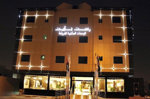 A hotel with a modern facade, multiple windows, and a sign in Arabic. - Rest Night Serviced Apartments - AL Nafal (Riyadh)