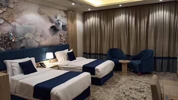 Habitación de hotel con dos camas, un mural grande en la pared, una cortina y dos sillones azules.