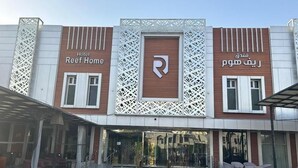 A hotel with a modern facade, a central logo, and a courtyard with seating. - Reef Home Luxury Hotel (Riyadh)