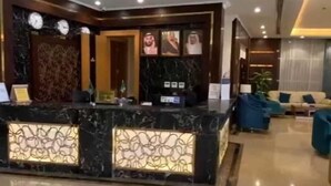 A hotel reception area with a marble reception desk, a seating area with sofas, and a wall-mounted clock. - Reef Home Luxury Hotel (Riyadh)