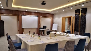 A conference room with a long table, blue chairs, a projector, and a whiteboard. - Reef Home Luxury Hotel (Riyadh)