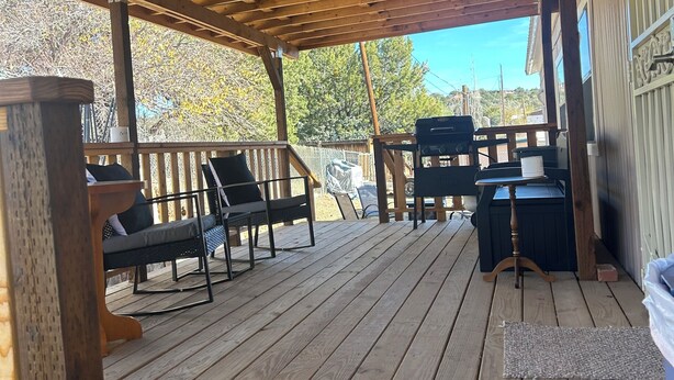Eine Holzterrasse mit Sitzgelegenheiten und einer Pergola.