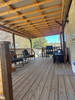 Une terrasse en bois avec des sièges d’extérieur et une structure en forme de pergola.