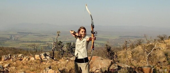 A person with a bow and arrow in a natural landscape. - Pakamisa Private Game Reserve (Pongola)