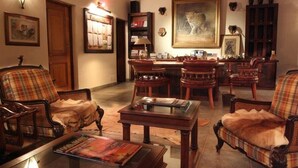 A traditional living room with wooden furniture, a fireplace, and a large painting of a leopard. - Pakamisa Private Game Reserve (Pongola)