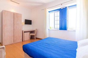 Un dormitorio con cama, escritorio y armario.