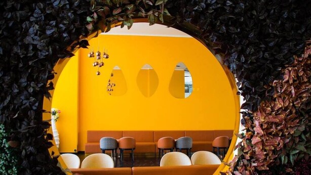 A yellow interior with a round table and chairs, surrounded by dark foliage. - New Hotel Nampula (Nampula)