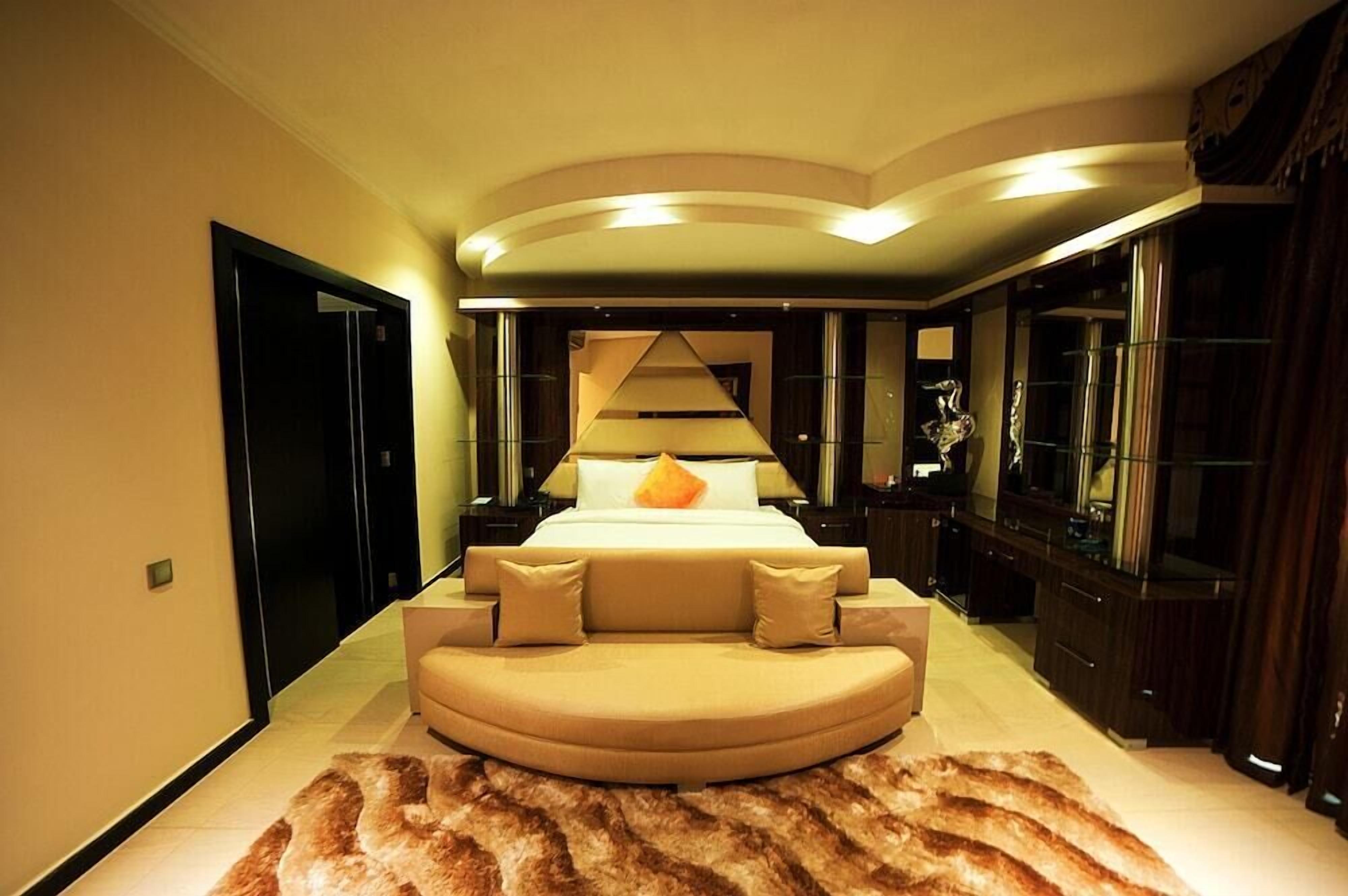 Un dormitorio moderno con una cama grande, un sofá curvo y una alfombra de piel.