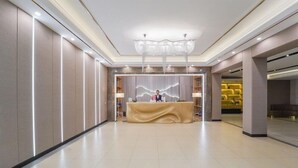 Zona de recepción de un hotel con mostrador, una lámpara de araña y diseño interior moderno.