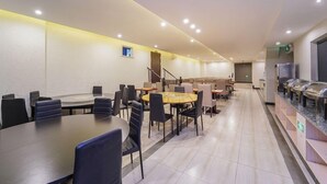 Un comedor moderno con mesas redondas, sillas y una barra de buffet.