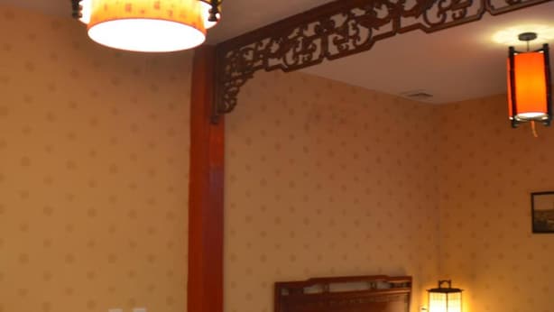 A traditional room with a bed, a wooden chair, a nightstand, and a wall-mounted lamp. - Qianmen Courtyard Hotel (Beijing)