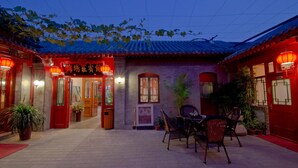 A traditional Chinese courtyard with tiled roofs, red lanterns, and potted plants. - Qianmen Courtyard Hotel (Beijing)