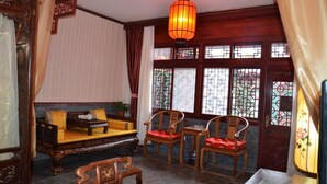 A traditional room with a sofa, two chairs, a table, and a decorative lantern. - Qianmen Courtyard Hotel (Beijing)