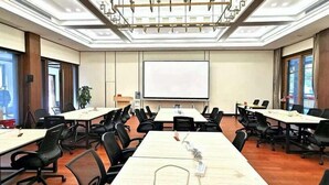 A conference room with multiple tables and chairs, a projector screen, and large windows. - Pipaxi Hunan Zhangjiajie (Zhangjiajie)