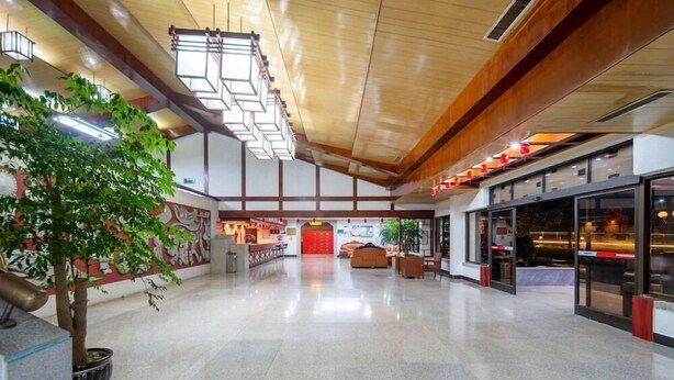 A spacious lobby with a high ceiling, a reception desk, seating area, and a large tree. - Pipaxi Hunan Zhangjiajie (Zhangjiajie)