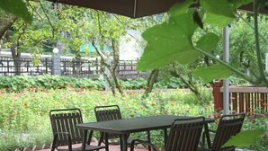 An outdoor patio with a table and chairs, surrounded by lush greenery and flowers. - Pipaxi Hunan Zhangjiajie (Zhangjiajie)