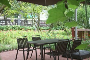 An outdoor patio with a table and chairs, surrounded by lush greenery and flowers. - Pipaxi Hunan Zhangjiajie (Zhangjiajie)