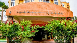 The entrance of the Isamilo Hotel with a modern design and a tropical garden in front.