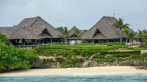 A beachfront resort with thatched-roof villas, a sandy beach, and lush greenery. - Zawadi Hotel Zanzibar (Dongwe)
