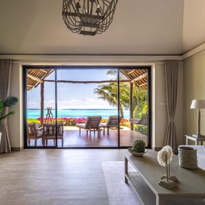 Een kamer met een grote schuifglazen deur die uitkomt op een balkon met uitzicht op zee.
