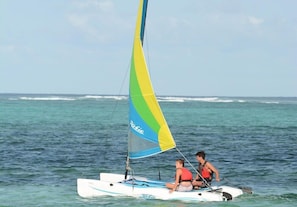 Un velero con dos personas a bordo, navegando sobre el agua.