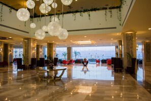 A spacious lobby with a polished marble floor, hanging crystal chandeliers, and red seating areas. - Tolip Taba Resort And Spa (Taba Heights)