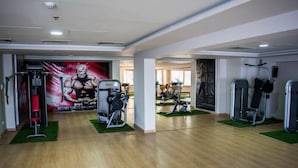 Une salle de sport équipée de divers appareils d’exercice, notamment un support à squats et des bancs de musculation.