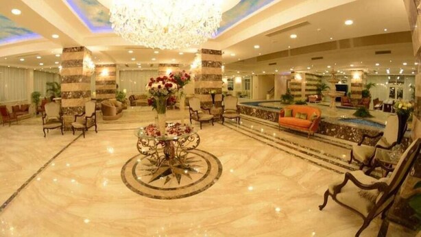 A spacious lobby with a chandelier, a pool area, and comfortable seating. - Guard Hotel (Cairo)