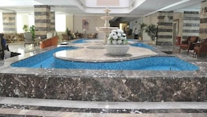 A lobby with a central fountain, seating areas, and a pool. - Guard Hotel (Cairo)