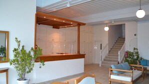 A spacious living area with a wooden bench, a potted plant, and a staircase leading to another level. - Faros (Spetses)