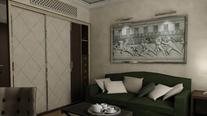 Una stanza con un divano verde, una poltrona bianca, un vassoio con teiera e tazze, e un'ampia opera d'arte incorniciata a parete.