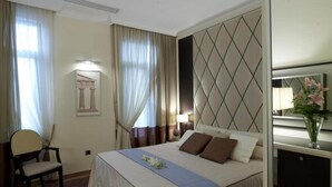 Una camera d'albergo con un letto, una sedia, una scrivania e uno specchio.