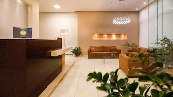 A hotel reception area with a reception desk, a sofa, a coffee table, and a chandelier.