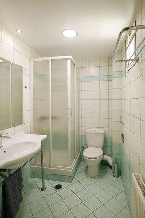 Un baño con ducha de vidrio, inodoro y lavabo con toallero.