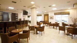 A hotel lobby with a bar area, seating arrangements, and a television. - Hotel Athina (Lamia)