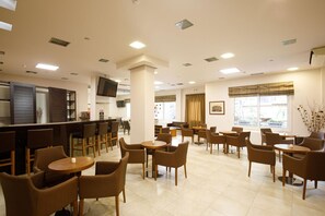 Eine Hotelhalle mit Barbereich, Sitzgelegenheiten und einem Fernseher.