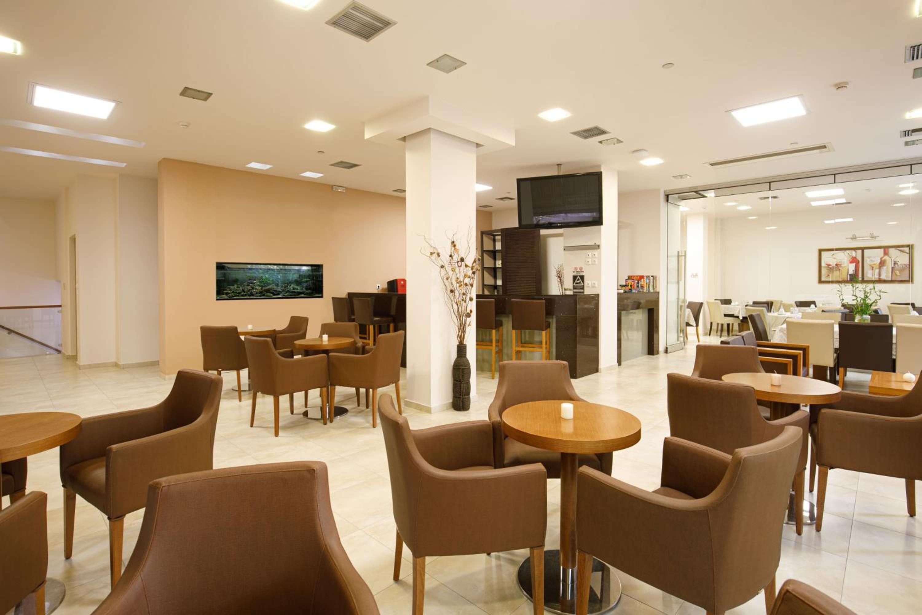 A hotel lobby with seating areas, a television, and a reception desk.