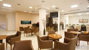 A hotel lobby with seating areas, a television, and a reception desk.