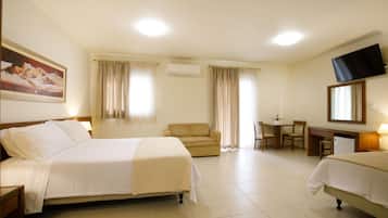 A hotel room with a bed, a sofa, a desk, and a television.