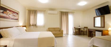 A hotel room with a bed, a sofa, a desk, and a television.