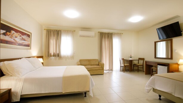 A hotel room with a bed, a sofa, a desk, and a television. - Hotel Athina (Lamia)
