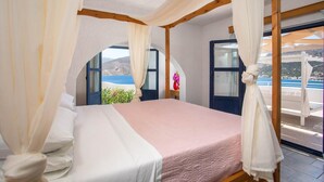 Une chambre à coucher avec un lit, des rideaux blancs et une vue sur la mer.