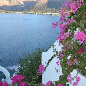 A coastal view with a body of water, a boat, and a building in the background. - Ilidi Rock Apartments (Tilos Island)