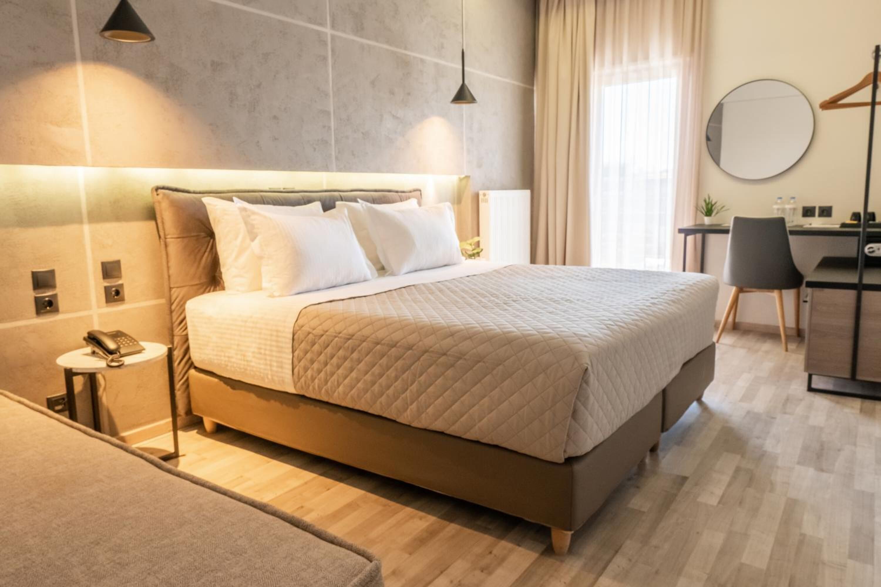 A modern hotel room with a large bed, bedside tables, a desk, and a chair.