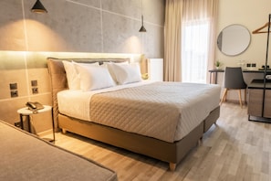 A modern hotel room with a large bed, bedside tables, a desk, and a chair. - Park (Larissa)