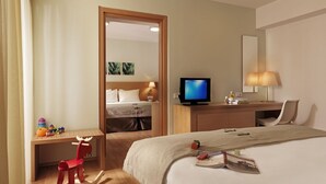 A hotel room with a bed, a desk with a chair, a television, and a mirror.
